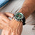 Herrenuhr am Handgelenk mit grünem Zifferblatt und schwarzem Lederarmband