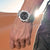 Festina Herrenarmbanduhr am Handgelenk mit schwarzem Zifferblatt und Metallband.