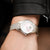 Damenuhr am Handgelenk: silbernes Meshband, schimmerndes Zifferblatt, FESTINA-Logo