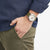 Montre homme au poignet avec boîtier argenté et bracelet en tissu vert olive