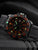 Herren-Armbanduhr im Detail, schwarze Lünette mit orange Ziffern und grünen Leuchtpunkten