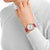 Montre pour femme avec bracelet en cuir rouge au poignet, cadran blanc rond.