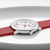 Alt: Gros plan d'une montre pour femme : cadran blanc sur bracelet en cuir rouge avec couronne de boîtier.