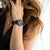 Damen-Armbanduhr am Handgelenk mit schwarzem Armband und schwarzem Zifferblatt