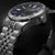 Bracelet de montre pour homme, gros plan : boîtier en acier inoxydable avec couronne et cadran bleu, index luminescents