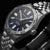 Montre bracelet pour homme, vue de côté : boîtier rond en acier inoxydable, cadran bleu foncé, bracelet en métal