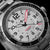Montre homme, gros plan : cadran gris avec aiguilles et chiffres des heures rouges