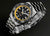 Montre homme de profil avec cadran noir, accents jaunes et bracelet en acier inoxydable