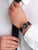 Mondaine Herrenarmbanduhr am Handgelenk mit schwarzem Lederarmband und goldfarbenem Gehäuse