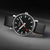 Montre avec cadran noir, aiguilles rouges et bracelet en cuir noir.
