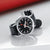 Montre Mondaine Stop2Go inclinée : cadran noir, boîtier argenté, bracelet en cuir noir