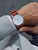 Herrenuhr mit braunem Lederarmband und weißem Zifferblatt am Handgelenk