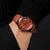 Bracelet de montre en bois au poignet avec bracelet en cuir marron et perforations, cadran rond