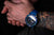 Montre de plongée pour homme au poignet avec bracelet bleu et index lumineux sur le cadran