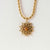 Collier avec chaîne dorée et pendentif soleil avec pierre marron sur fond clair