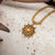 Pendentif soleil sur chaîne dorée avec cabochon marron, sur surface de pierre claire