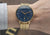 Sternglas Armbanduhr am Handgelenk mit dunkelblauem Zifferblatt und goldfarbenem Meshband