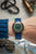 Herrenuhr am Handgelenk: blaues Textilband, bronzefarbenes Gehäuse, grünes Zifferblatt