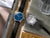Armbanduhr mit blauem Zifferblatt und schwarzem Lederband, Uhrwerk offen