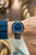 Sternglas Herrenarmbanduhr am Handgelenk: blaues Zifferblatt, schwarzes Lederband, gelbe Akzente