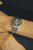Herrenarmbanduhr am Handgelenk mit schwarzem Zifferblatt, Metallarmband und Datumsfenster