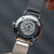 Rückseite einer silbernen Damenarmbanduhr mit graviertem Motiv am Mesh-Armband