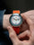 Montre bracelet pour homme au poignet avec bracelet textile orange et cadran multicolore