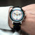 Herrenuhr am Handgelenk, schwarzes Lederband, silbernes Chronographenzifferblatt mit Farben