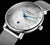 Montre pour femme avec boîtier argenté, cadran blanc, aiguilles bleues et bracelet en maille