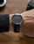 Montre bracelet pour homme au poignet avec bracelet en cuir noir et cadran sombre