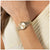 Damenarmbanduhr: rundes goldfarbenes Zifferblatt mit Metallarmband und Faltschließe.