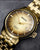 Bracelet pour homme avec boîtier doré et cadran doré, index fins et date.
