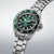 Montre homme de profil avec cadran vert, boîtier en acier et index sur la lunette