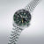 Bracelet de montre pour homme, vu de côté : bracelet en acier inoxydable, cadran vert foncé avec affichage de la date