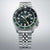 Montre bracelet homme de face : bracelet en acier inoxydable, cadran sombre avec date et GMT