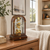 Horloge de table en bois sur table en bois, arche en verre, mouvement doré avec chiffres romains