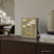 Wanduhr-Wortuhr in Messingoptik mit LED-Zeitwörtern, auf Sideboard stehend