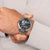 Herrenarmbanduhr: silbernes Metallband, schwarzes Skelettzifferblatt mit Indexen und Chrono-Subdials
