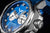 Herrenarmbanduhr im Detail: Seitenansicht mit Krone und Druckknopf, blaues Zifferblatt
