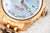 Montre femme gros plan : cadran bleu, lunette dorée, affichage de la date à 5 heures.