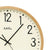Horloge murale avec cadran beige, aiguilles noires et cadre en bois clair, AMS.
