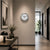 Horloge murale ronde sur un mur avec cadran blanc, bordure argentée, aiguilles noires, trotteuse rouge