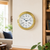 Horloge murale avec boîtier rond en laiton, cadran blanc et aiguilles bleues, index romains.