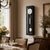 Horloge murale avec boîtier noir, cadran blanc et pendule argentée sous verre.