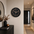 Horloge murale ronde avec cadran noir, aiguilles et chiffres en or rose, Hermle