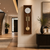 Horloge murale en bois marron avec cadran blanc, barres de son dorées et pendule