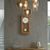 Horloge murale en bois avec cadran blanc, bordure dorée et pendule ronde.