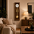 Horloge murale en bois dans un salon : cadran blanc, barres de son dorées et disque de pendule