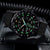 Montre homme avec boîtier rond noir et chiffres luminescents, bracelet textile noir