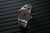 Bracelet de montre pour homme avec index luminescents sur le cadran et bracelet en cuir foncé.